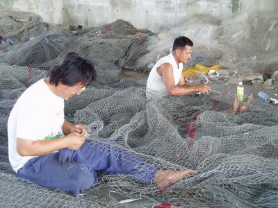 為了下次豐收，辛勤補網的漁民